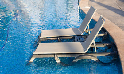 BEACH CHAIRS (CHESLONG) INSIDE BLUE POOL WITH CRYSTAL OUTDOOR WATER AND SPACE FOR TEXT