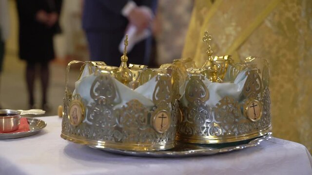 Crowns in the church at the wedding. Orthodox Christian or Catholic cathedral. Gold hats with crosses for marriage. The priest conducts a liturgy, reads prayers.