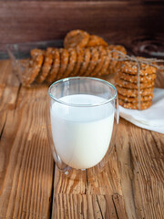Homemade cookies with pieces of seeds and a bottle of milk laid out in a stack on a silatakes on a rustic table.