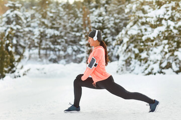 A young woman does a warm-up before training in the snow in winter.