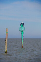 Green beacon next to a water mark from a tree trunk for navigation in the North Sea on the way to...