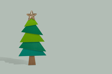 Christmas tree made of paper and christmas star decoration on a gray background.