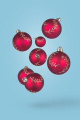 Red Christmas ornaments flying on blue background. Happy holidays. New year minimal concept.