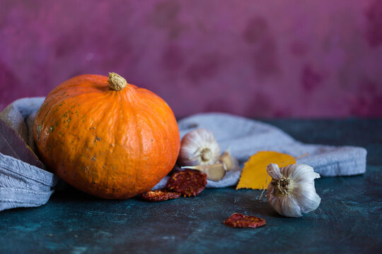 Autumn harvest capture with orange pumpkin and garlic on painted background