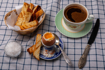 an egg on a stand and cup of coffee