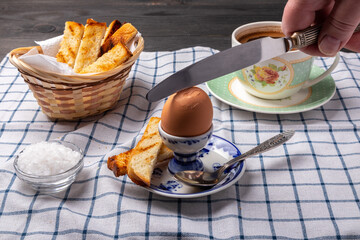 egg on a stand, croutons in a basket and a cup of coffee