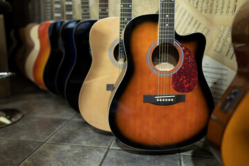 Many different colored acoustic guitars next to each other