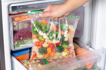 Plastic bags with different frozen vegetables in refrigerator.
