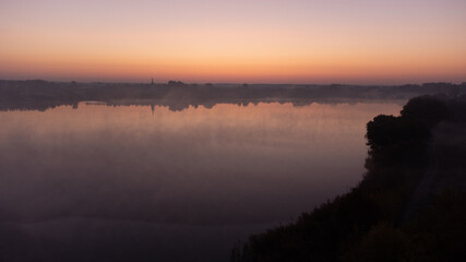 Beautiful foggy morning. Fog over autumn lake at sunrise moment. Wide panorama.