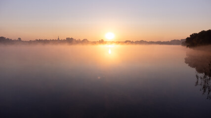 Beautiful foggy morning. Fog over autumn lake at sunrise moment. Wide panorama.