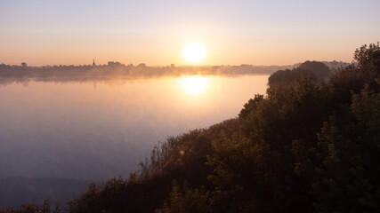 Fototapeta na wymiar Beautiful foggy morning. Fog over autumn lake at sunrise moment. Wide panorama.