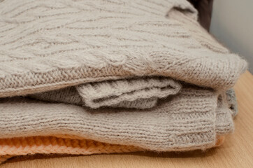 A stack of cozy knitted sweaters on a wooden table. Retro style. Warm concept