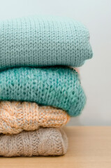 Detail of a stack of woolen sweaters of various colors beige, blue, hand-woven. Vertical photography.