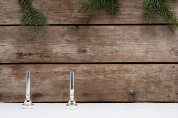 Two trumpet mouthpieces representing the second advent on a wooden background with some small pine tree branches