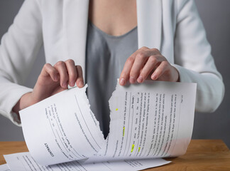Torn contract in hands. Terminated agreement concept. Ripping paper document and breaching rules.