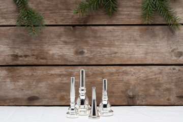 A French horn, trumpet, trombone and tuba mouthpiece in the spirit of christmas on a wooden...