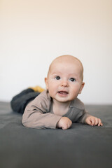 Cute 4 months old baby boy enjoying standing on his tummy. 