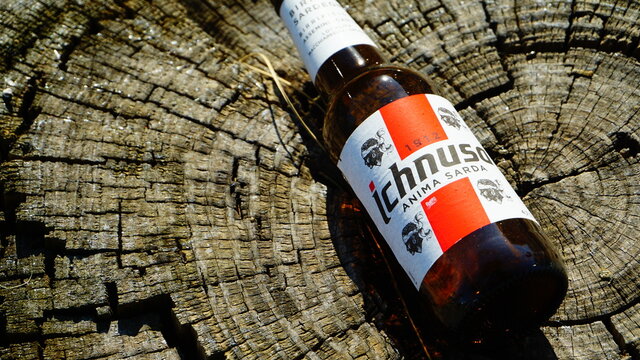 Rome, Italy - March 03, 2019: Ichnusa empty beer bottle left on tree trunk. famous Sardinian beer, produced in Assemini. It takes its name from the ancient Latin name for Sardinia, Hyknusa