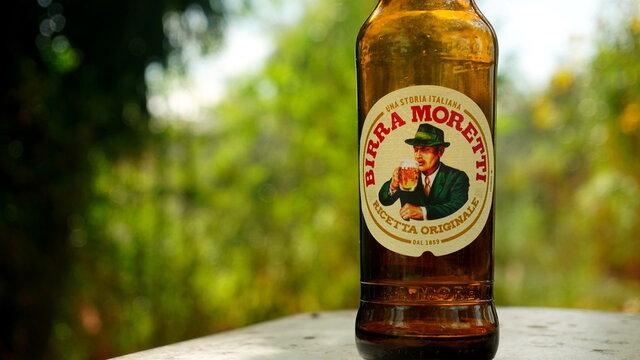 Rome, Italy: October 20, 2018: Empty bottle of Moretti beer on a wall with a blurred background. is an Italian brewing company, founded in Udine in 1859 by Luigi Moretti acquired in 1996 by Heineken