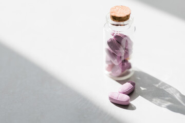 pink vitamin pills in glass jar