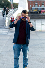 Fototapeta premium happy young man with a beard putting on sunglasses outdoors in a park dressed for work