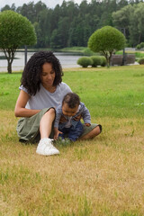 Young beautiful mother is playing on the grass with her child