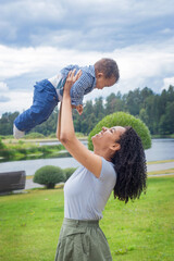 Young beautiful dark-skinned mother holds her baby up