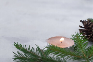 An empty space for text. Christmas background. Spruce branches with candle and cone on a light background.