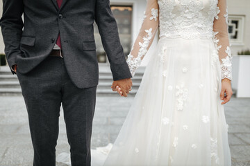 Bride and groom holding hands close-up