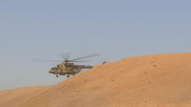 A combat military helicopter takes off from behind
