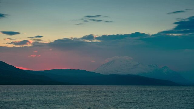 Time lapse of sunset in mountain landscape in Swedish Stora Sj&ouml;fallet national park, snow covered mountains in the back, clouds moving in the sky, lake in the front, North Sweden
