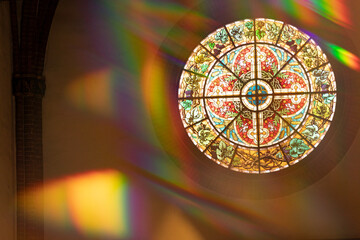 A round stained glass window with light leaks and artifacts coming from a glass prism