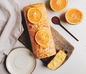 orange cake with sugar syrup on wooden board and light background