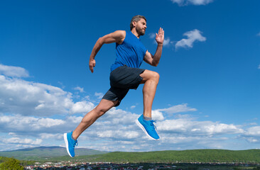 energetic man athlete with muscular body run in sportswear outdoor on sky background, jogging