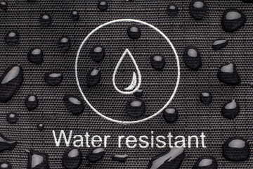 Black waterproof fabric with water droplets. The symbol of a drop of water is applied to the...