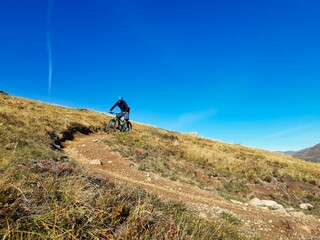 Enduro ride with steep bend, banked curve, Swiss Mountain Alps at Davos Switzerland. With blue clear sky and great view