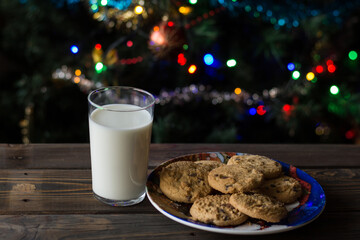 Cookies and a glass of milk on a Christmas tree background.