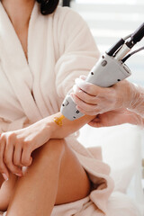 Naklejka premium Beautician removes hair on beautiful female hands using a laser. Laser epilation and cosmetology. Cosmetology and SPA concept.