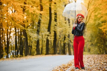Beautiful girl with umbrella at autumn park.