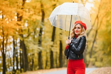 a girl walks in the autumn park under an umbrella