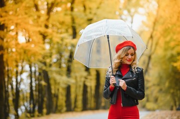 Beautiful girl with umbrella at autumn park.