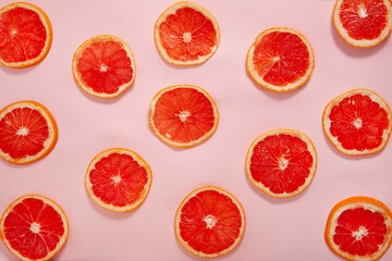 Pattern with sliced blood grapefruit fruits on a pink background, Flat lay