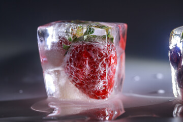 Frozen red sweet summer berries in ice. Cold freeze, winter background, frozen water.
