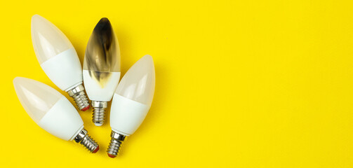 Broken and burn out LED light bulb after fire. Home safety concept. Top view, copy space, yellow background