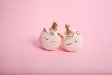 Two white sleepy unicorn French macaron cookies against the pastel pink background, Contemporary art food 