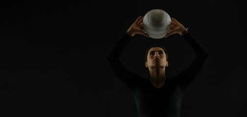 Volleyball girl hold and kick ball on dark background. Player doing sport workout online....
