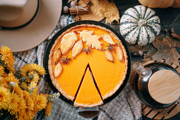 autumn composition with pumpkins, yellow tea flowers, warm plaid and hat and pumpkin pie in the center of the frame © Mikhaylovskiy 