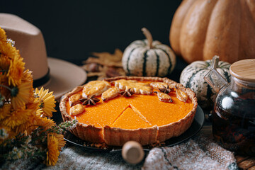 autumn composition with pumpkins, yellow tea flowers, warm plaid and hat and pumpkin pie in the center of the frame © Mikhaylovskiy 