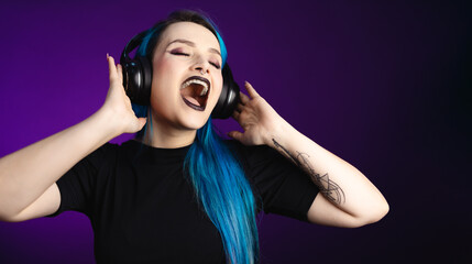 Fototapeta premium Large banner Woman in black friday, shopping, expressions, with headphones listening to music and dancing, blue hair, copy space, black background, neon style for websites, billboards and boards