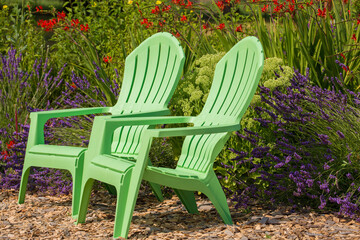 Two bright, mint-green plastic chairs against  vibrant crocosmia and beautiful lavender field in Sequim, WA
